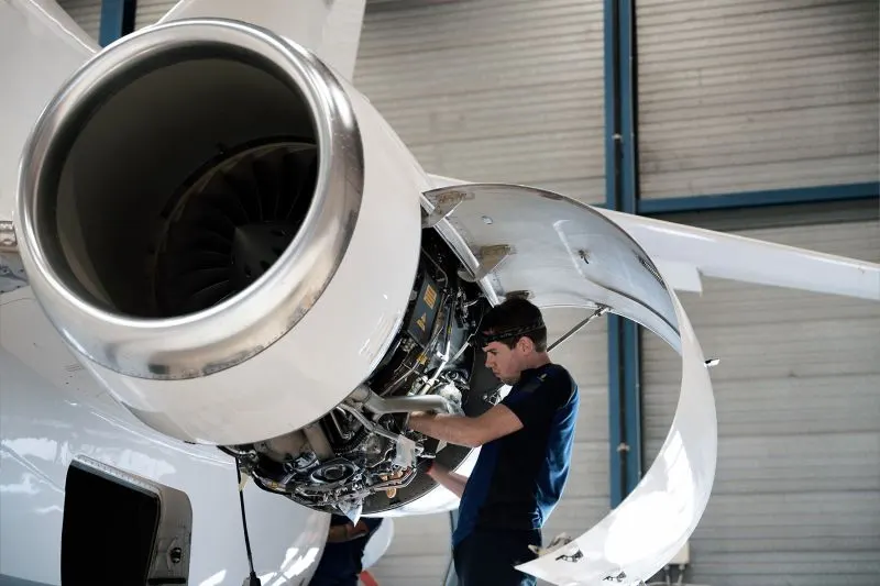 Mecânico inspecionando o motor turbofan de um jato executivo